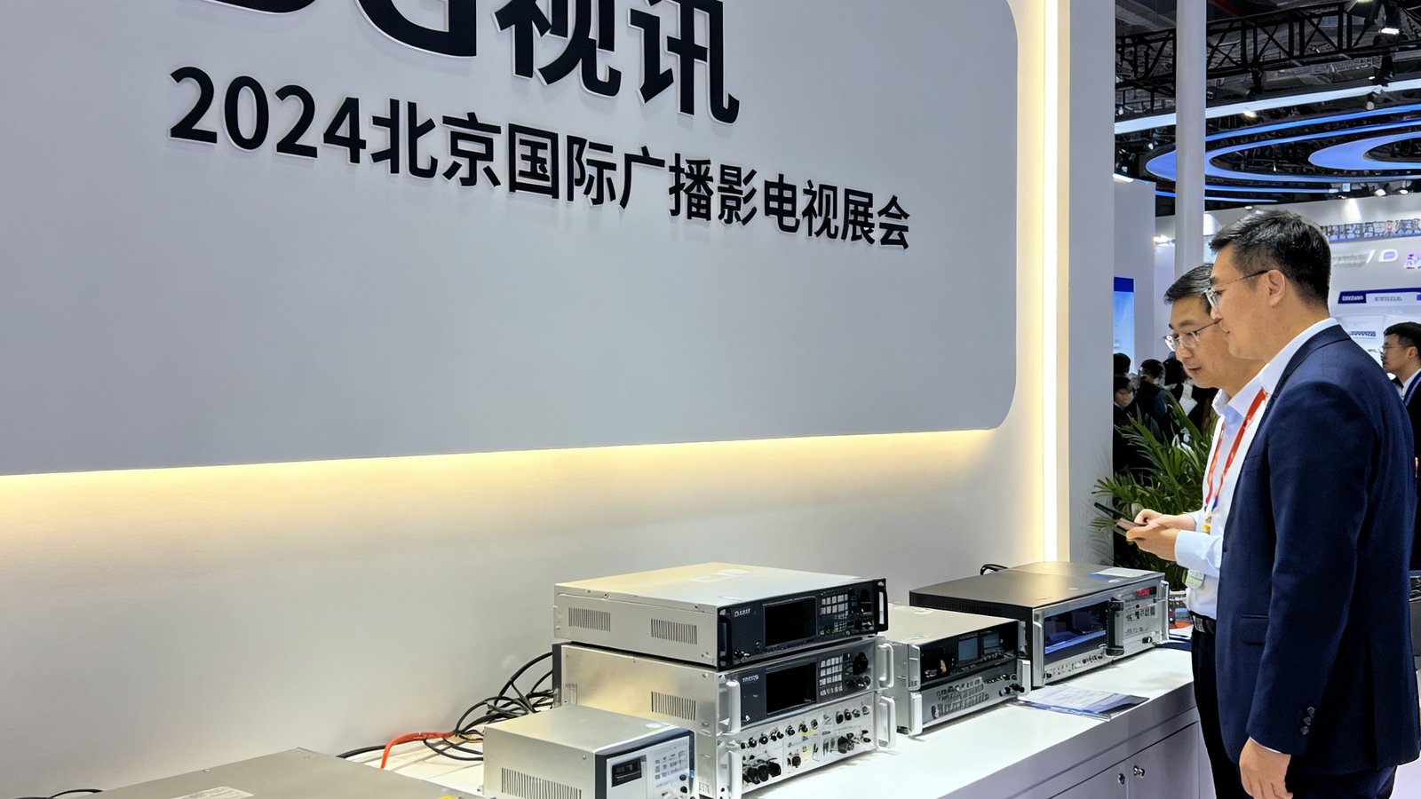 DG视讯在2024北京国际广播电影电视展览会上的展位，展台上陈列着全线传输设备产品，参观者正在咨询技术参数